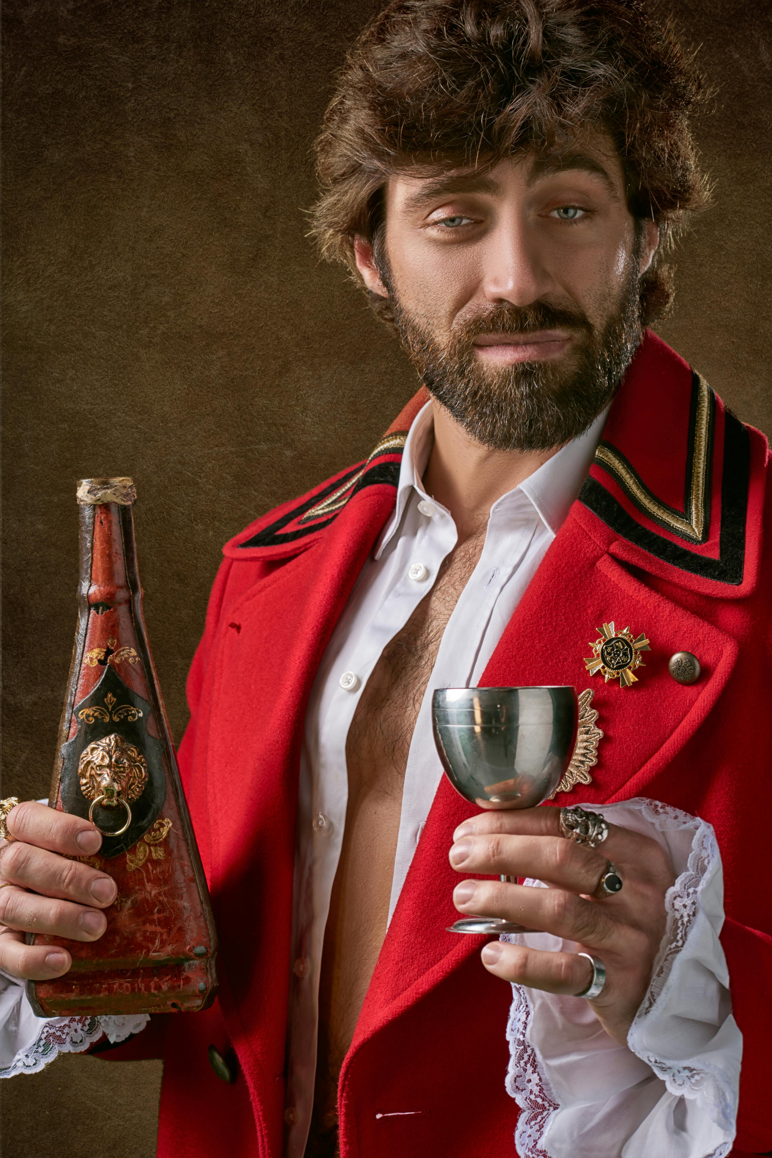 man holding red and black bottle