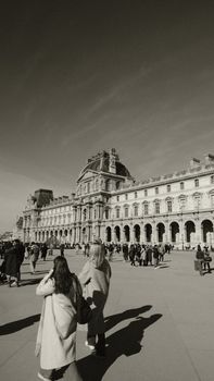 Crowded scene outside the Louvre Museum on a sunny day.