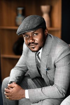 Elegant portrait of a man in a gray suit and hat indoors. Perfect for fashion and lifestyle themes.
