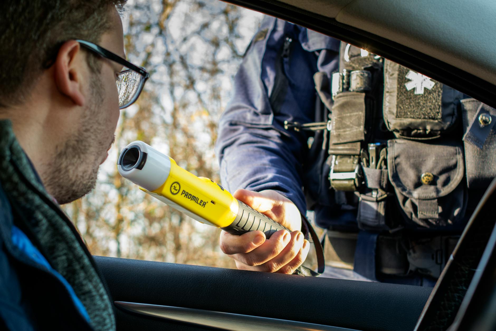 A police officer conducts a breathalyzer test on a driver during a roadside traffic check.