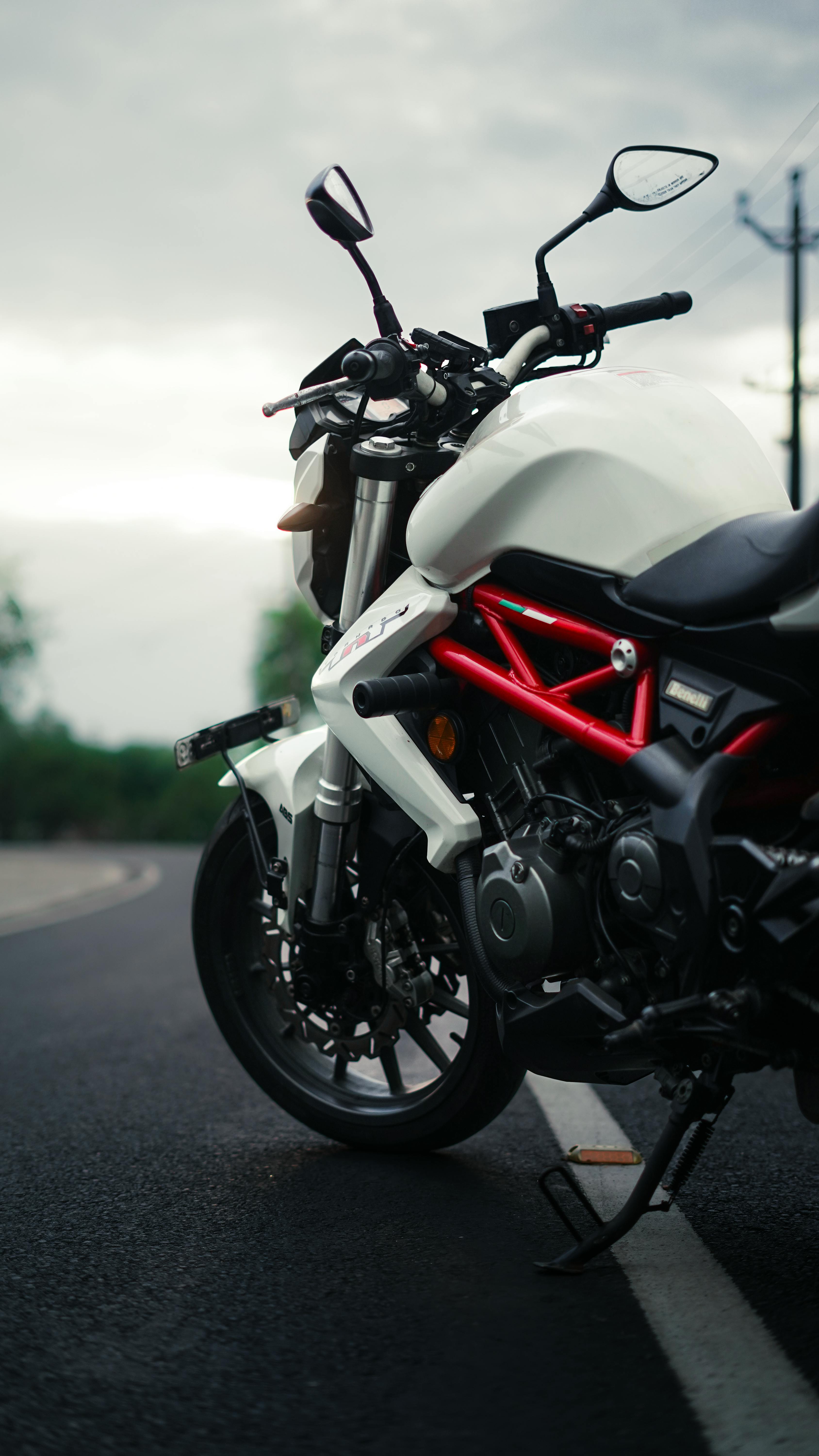 Dynamic shot of a white superbike parked on a wet road under overcast skies.