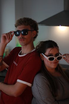 Two friends posing with fashionable sunglasses in a modern kitchen setting.