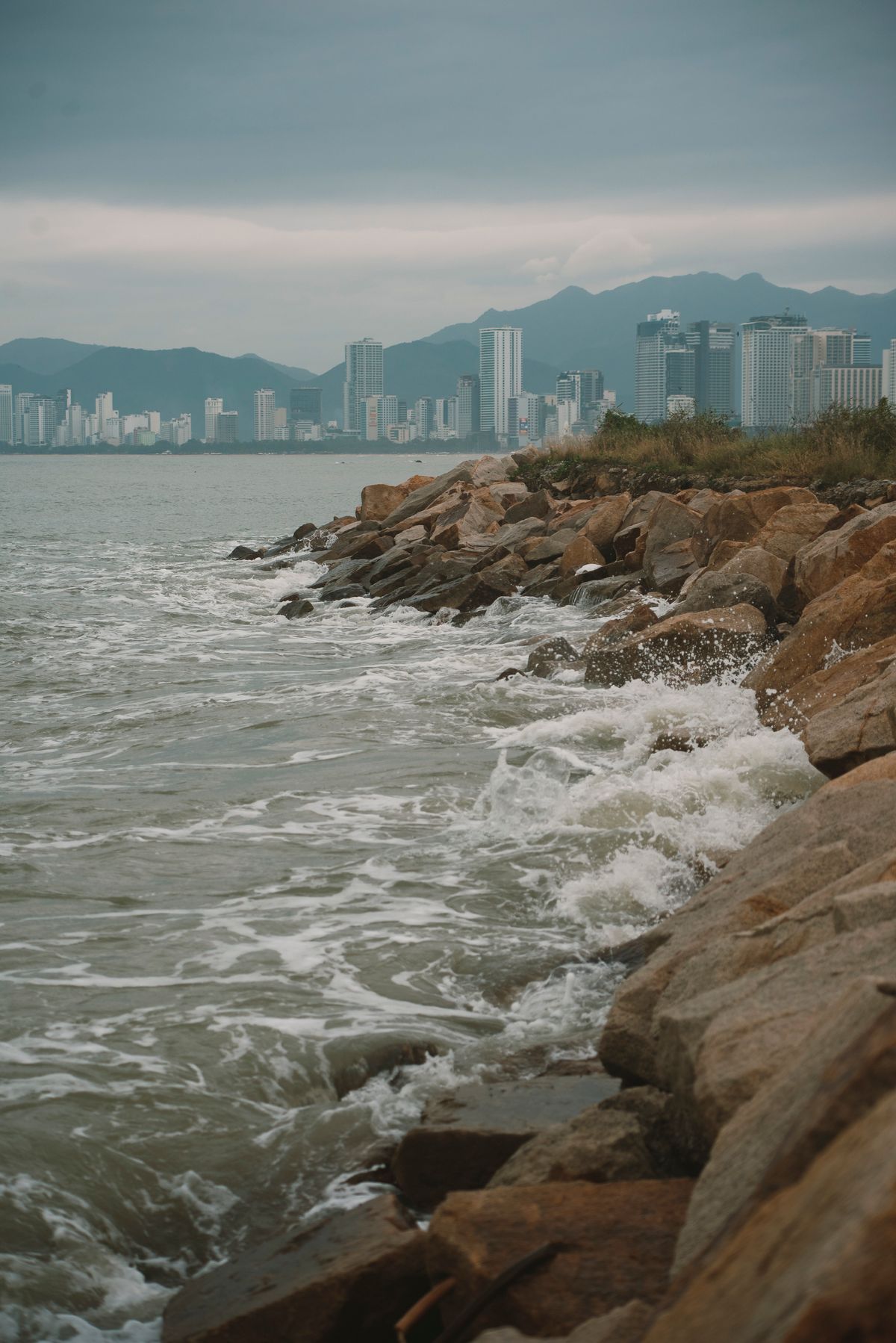 Nha Trang shoreline and distant city buildings beyond coastal rocks