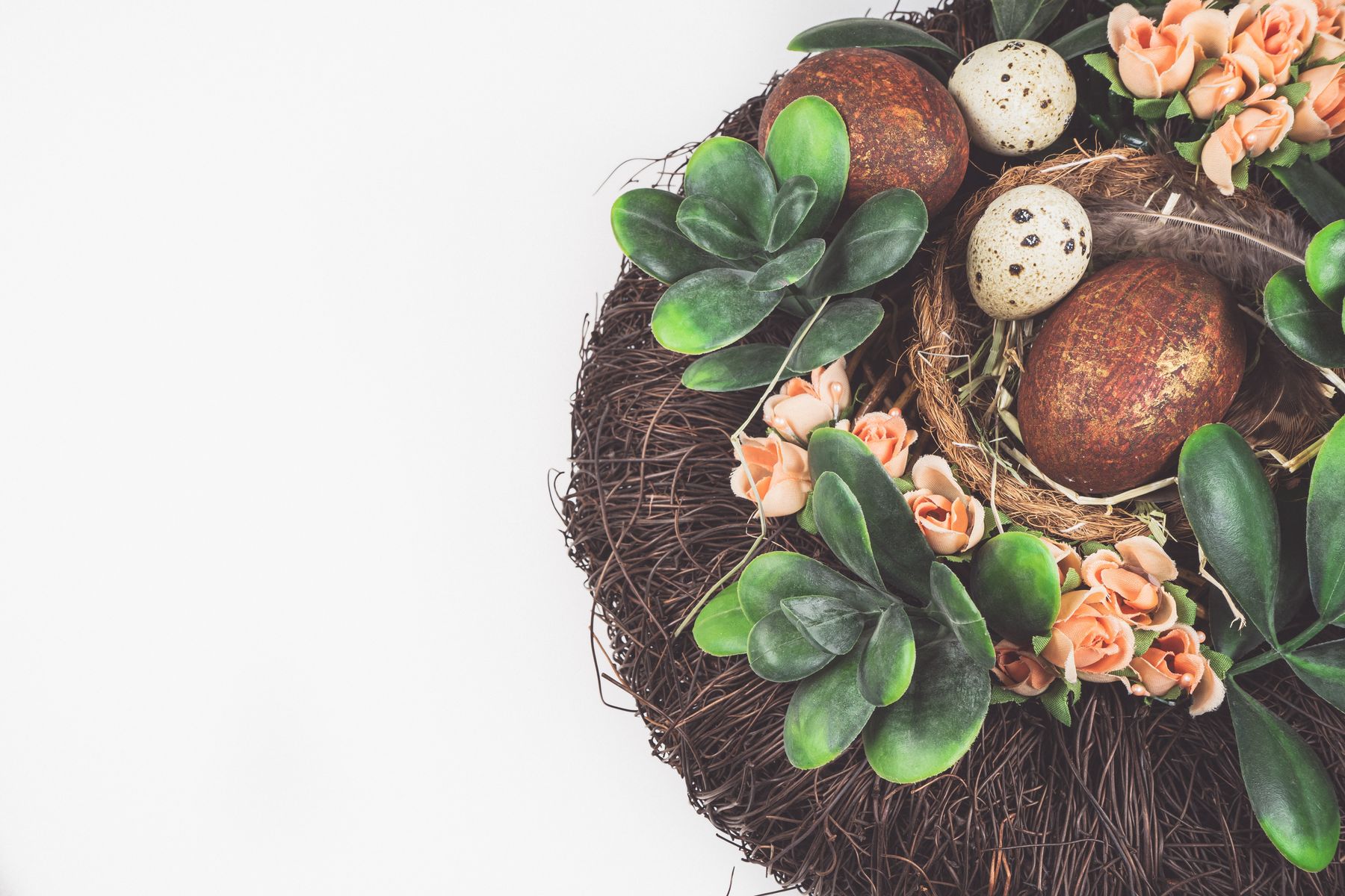 Spring nest with decorative eggs, flowers and greenery
