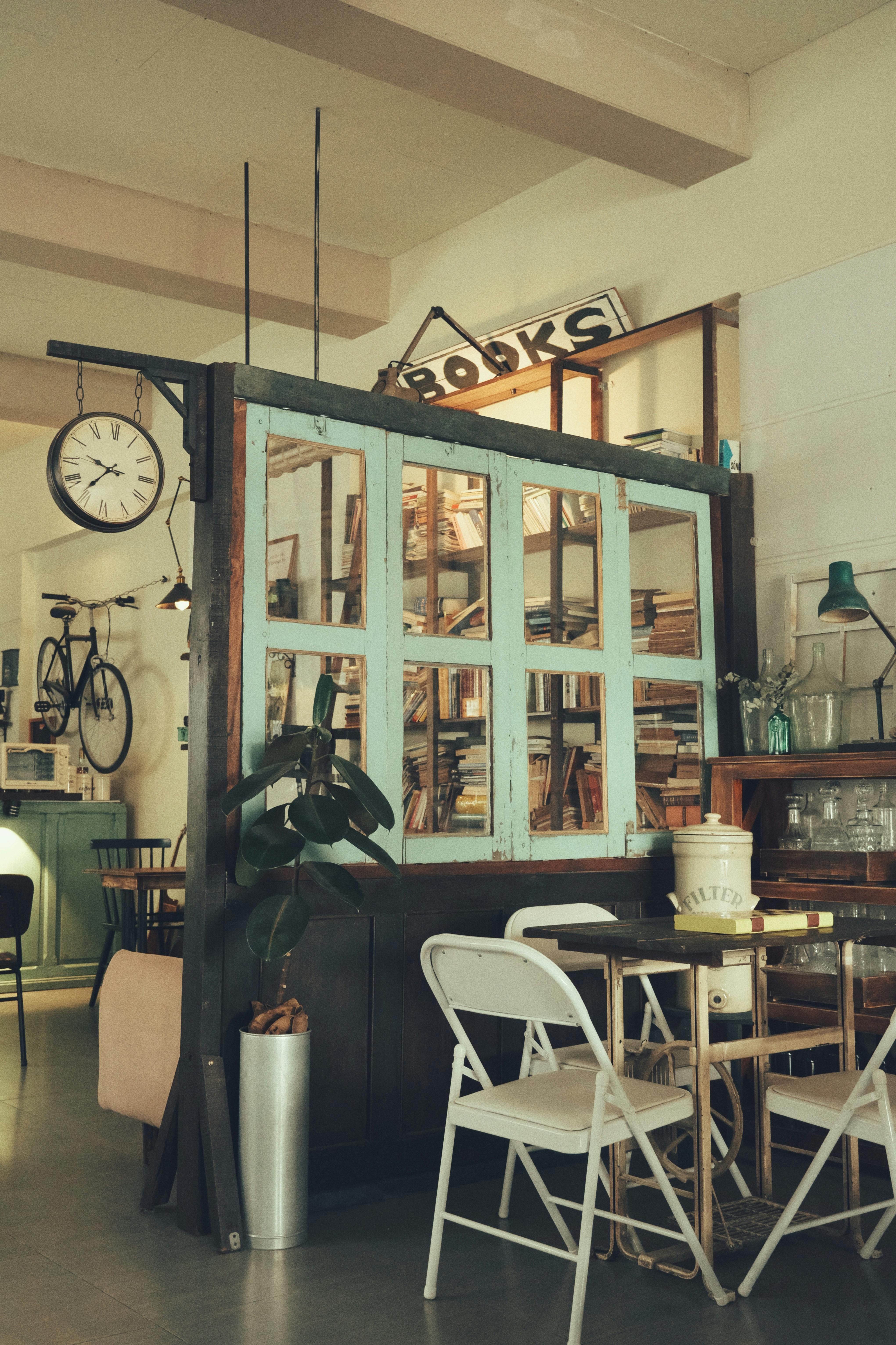 Free Charming library-themed cafe with vintage decor and cozy seating arrangement creating a warm ambiance. Stock Photo