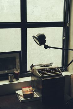 A vintage typewriter by a window with soft lighting and books, evoking nostalgia.