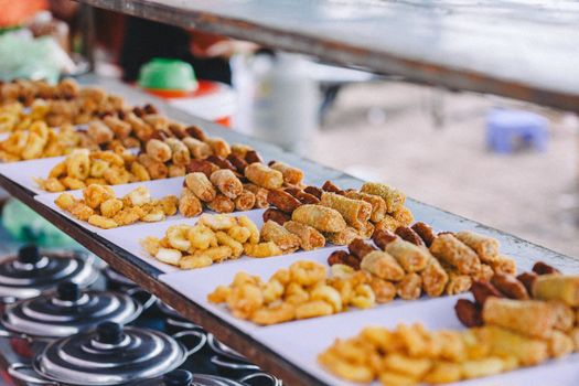 A variety of crispy and golden fried snacks beautifully arranged at an outdoor market stall.