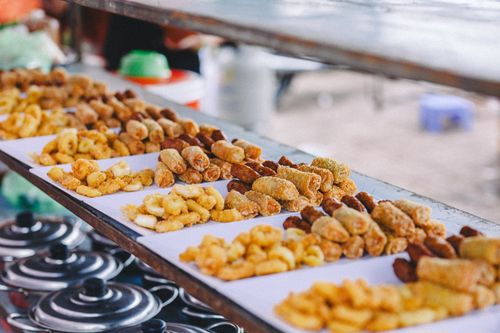 Free A variety of crispy and golden fried snacks beautifully arranged at an outdoor market stall. Stock Photo
