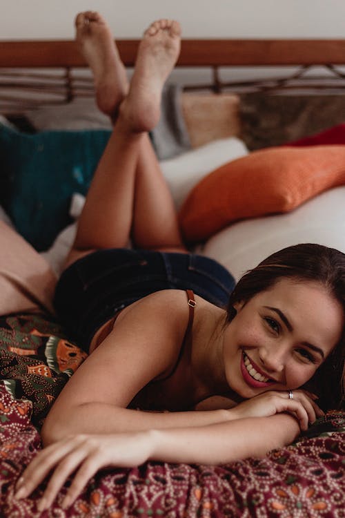 Woman Smiling while Lying Down on Bed
