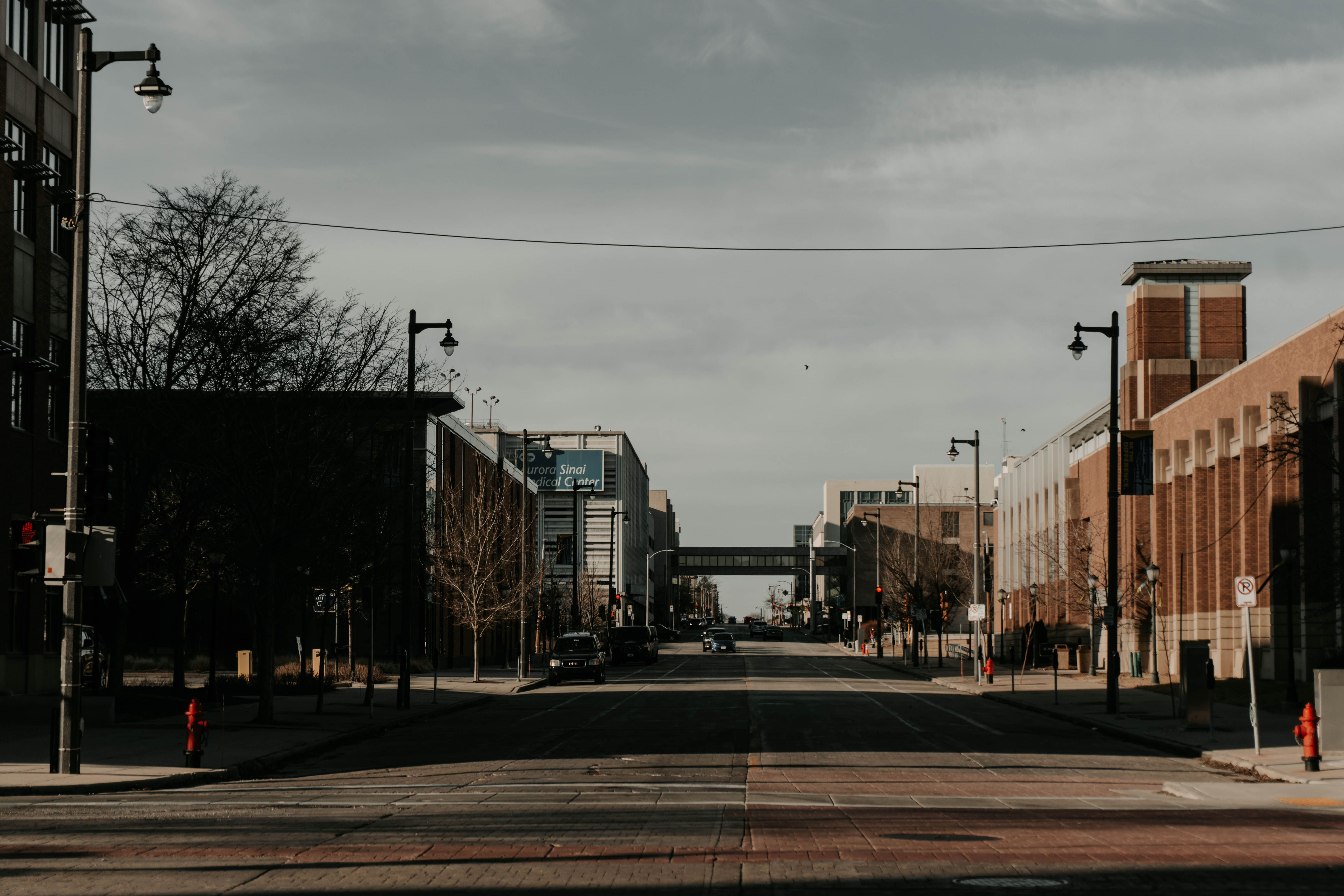 A moody city street in Milwaukee displaying buildings and street lamps under a cloudy sky.