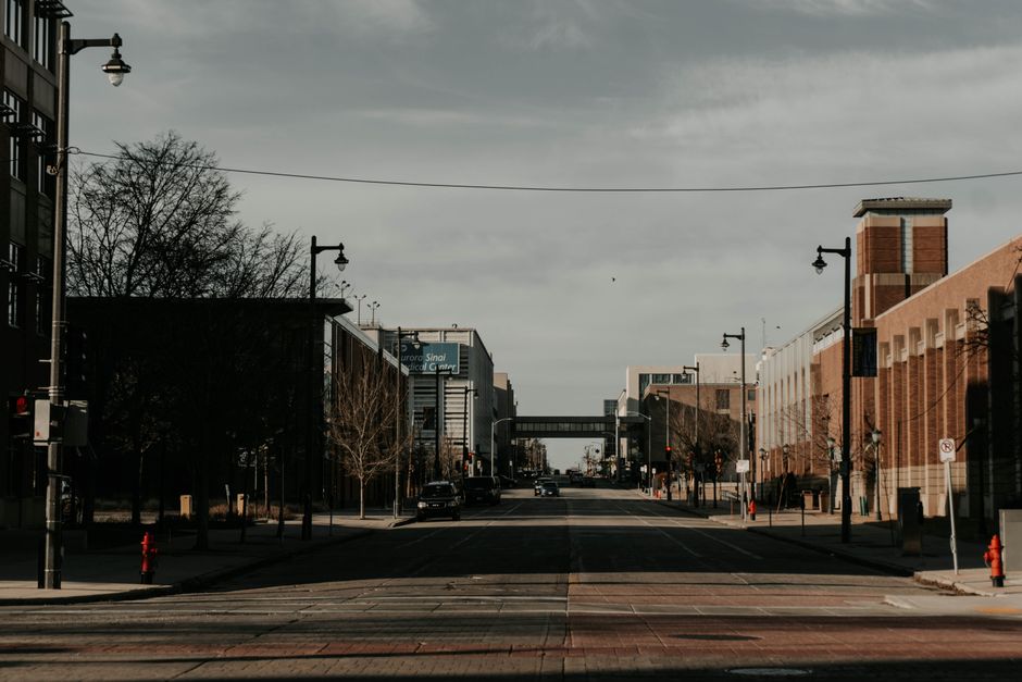 A moody city street in Milwaukee displaying buildings and street lamps under a cloudy sky.