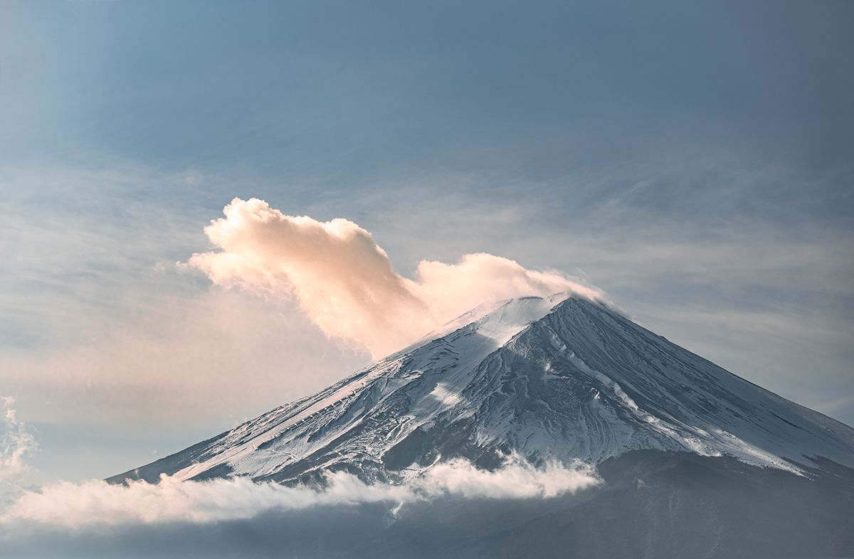 Snow-capped Mount Fuji glowing in golden light at sunrise, viewed from the northern shore of the Fuji Five Lakes in Yamanashi Prefecture