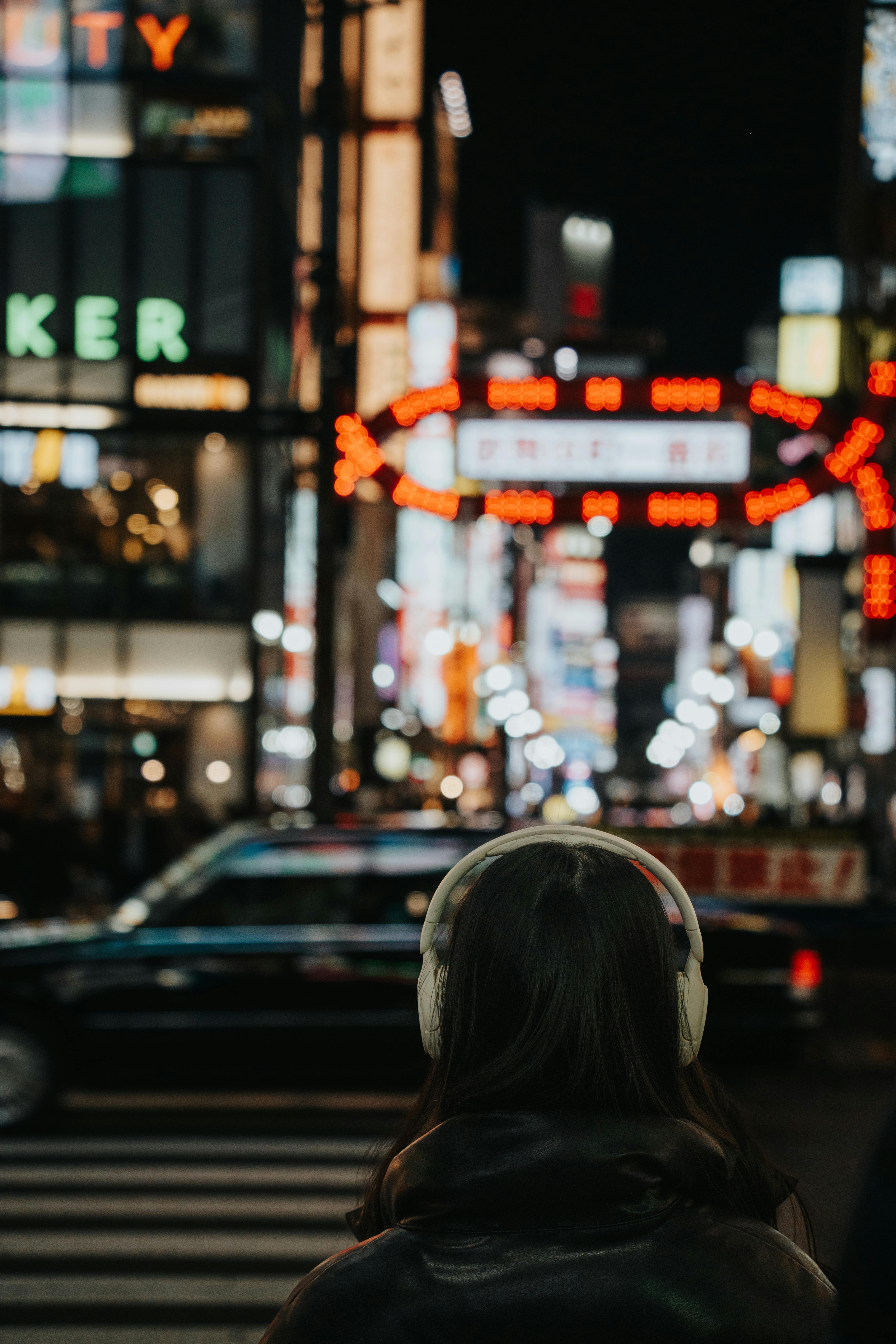 A person explores vibrant city streets at night, surrounded by neon lights and bustling traffic.