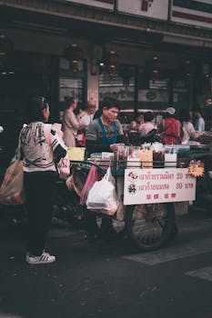 A vibrant street food vendor serving customers in a busy Bangkok market.