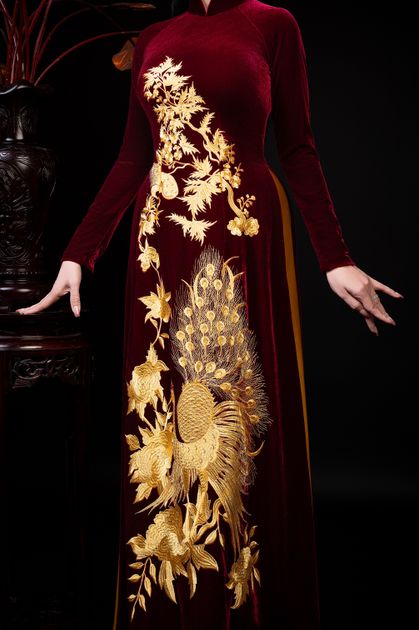 Burgundy velvet dress with intricate gold embroidery featuring peacock and floral motifs, demonstrating how traditional embroidery elevates contemporary fashion.
