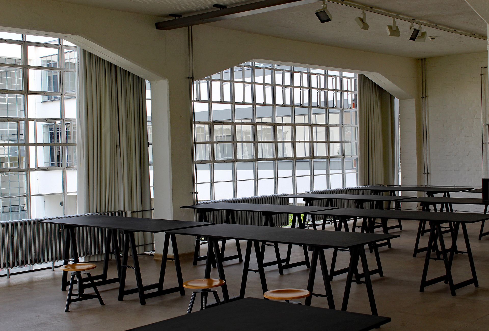 A minimalist view of a Bauhaus school classroom with large windows in Dessau, Germany.
