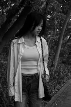Black and white portrait of a woman walking through a forest.