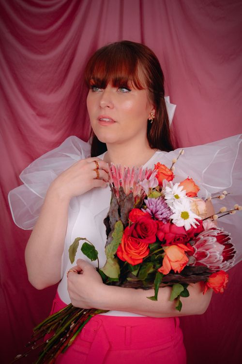 Free A woman holding a vibrant flower bouquet against a pink backdrop. Stock Photo