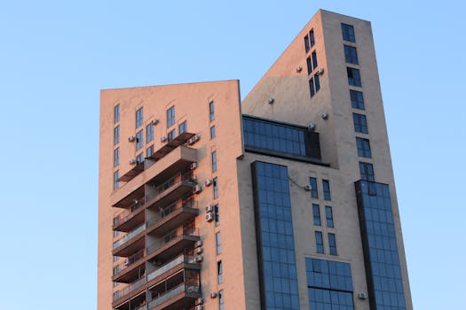 Contemporary high-rise apartment building with a unique geometric design against a clear blue sky.