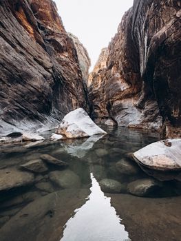 Serene view of Snake Canyon, showcasing smooth rocks and tranquil water reflections in Oman.