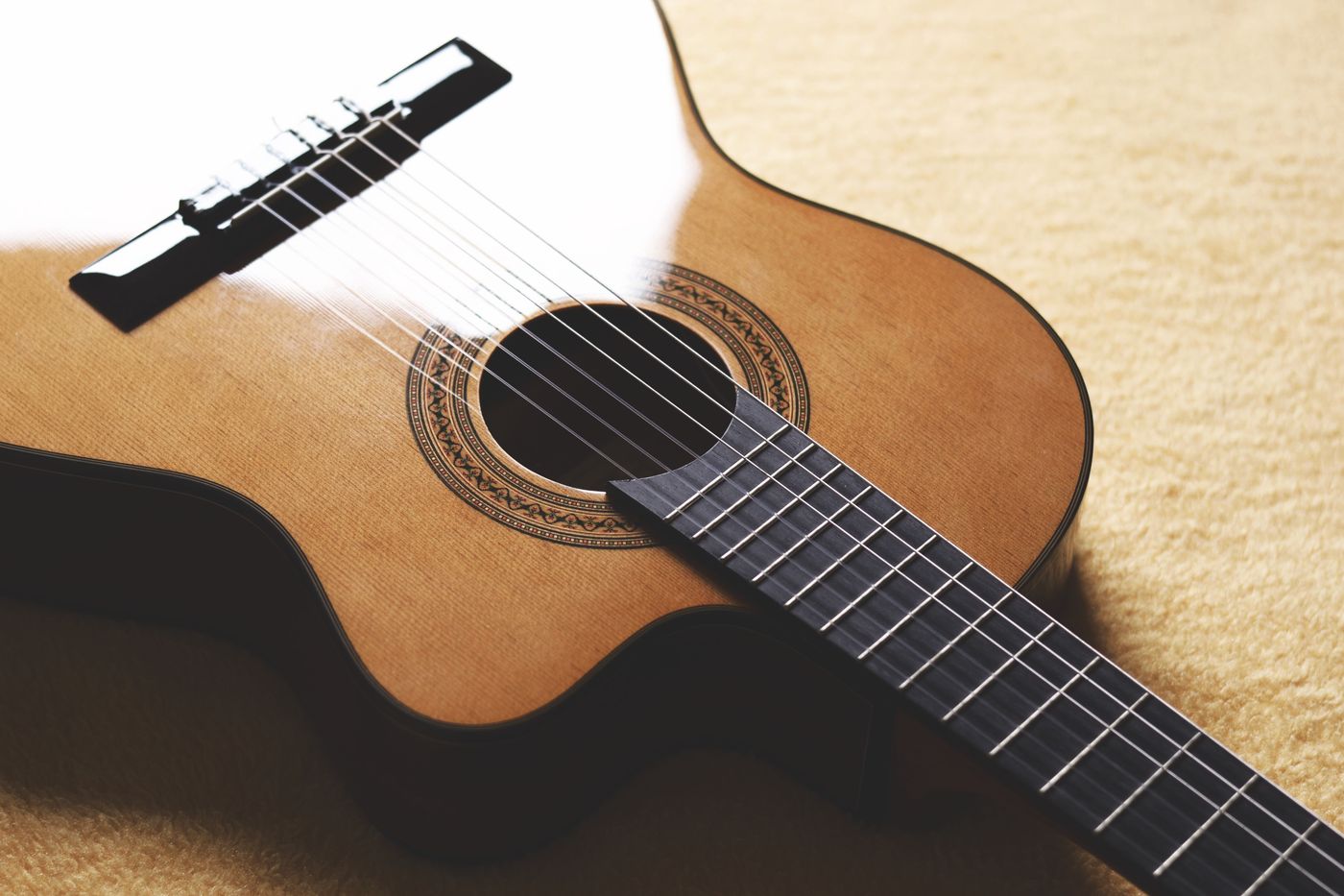 A classical guitar's wooden body, bridge and nylon strings in warm light