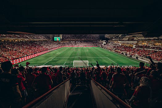 An exciting football match with passionate fans filling the stadium under bright lights, capturing sports energy.