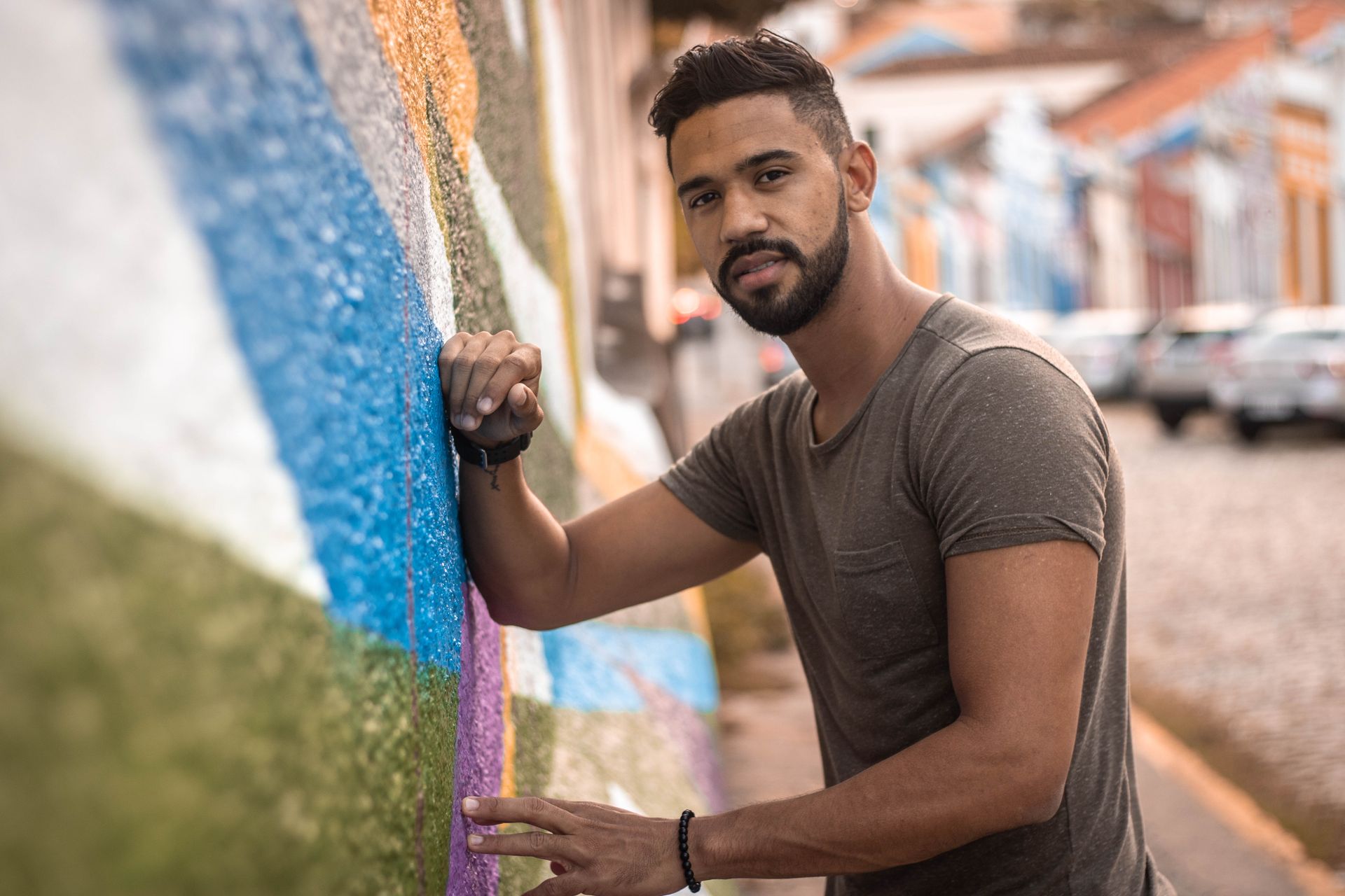 A stylish young man poses by a colorful graffiti wall in Olinda, Brazil.