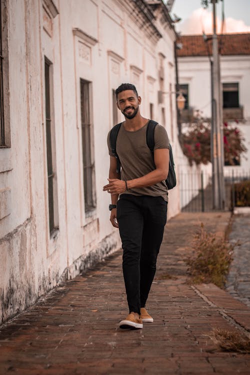 Man in Gray T-shirt Walking Beside Wall