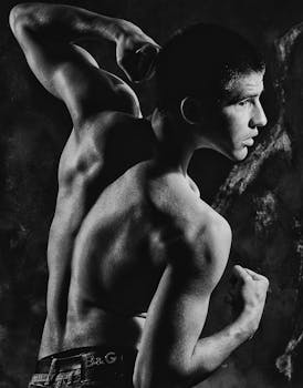 Dynamic black and white portrait of a muscular man in an athletic pose.