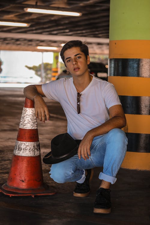 Homem De Camiseta Branca Sentado Ao Lado Do Cone De Trânsito