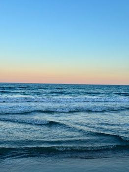 Tranquil evening view of ocean waves under a colorful sunset in Alicante, Spain.