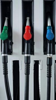 Close-up of vibrant green, red, and blue gas pump handles at a station.
