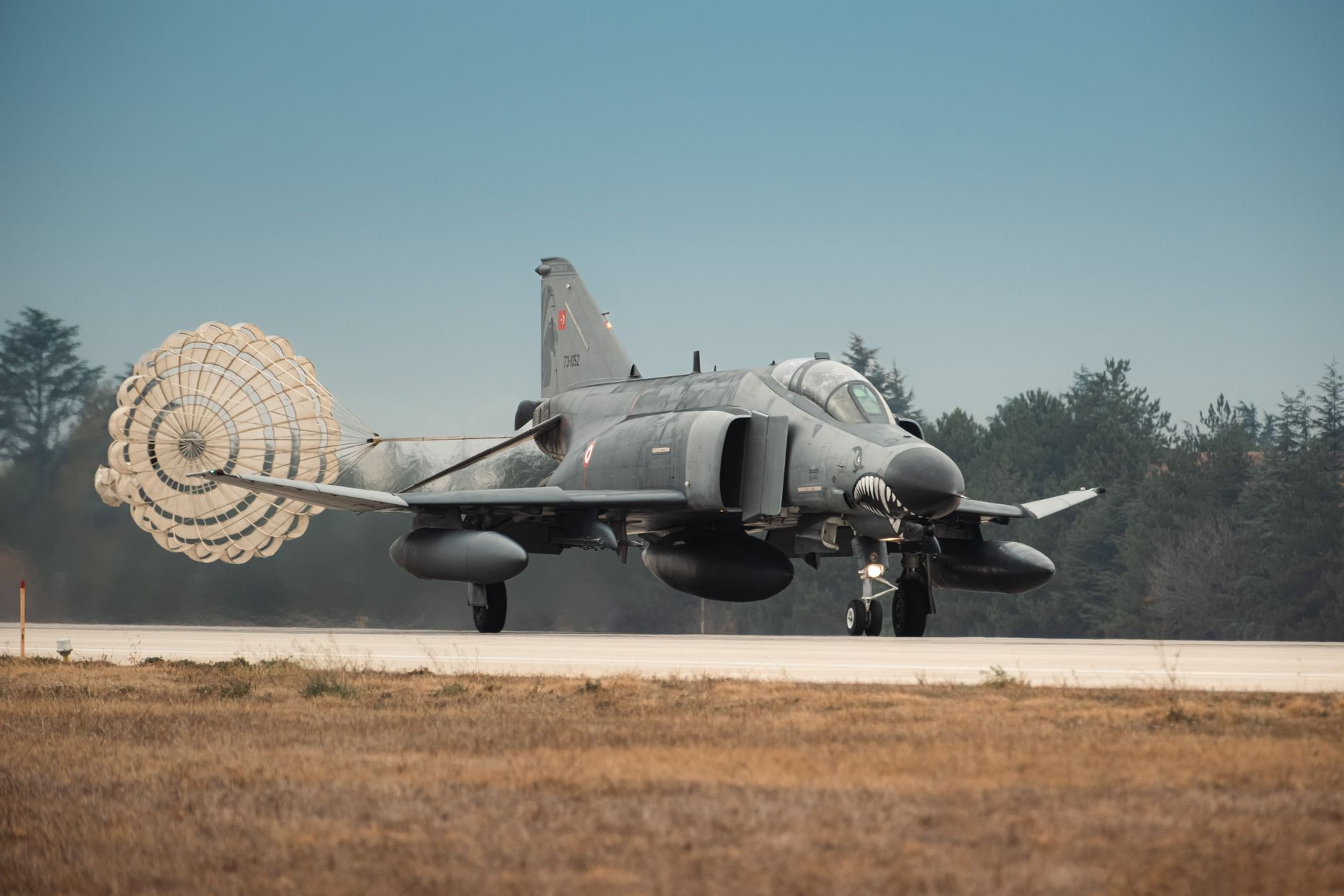 Turkish Air Force jet fighter landing with parachute deployed on runway in Türkiye.