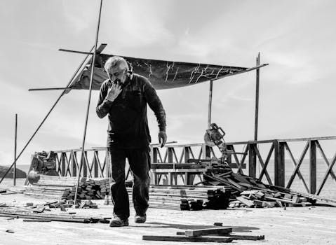 Un operaio edile pensieroso su un tetto in bianco e nero.