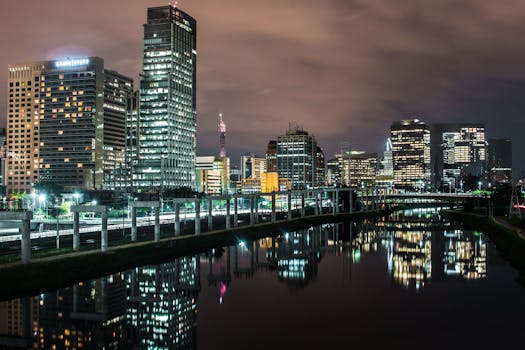 夜晚，圣保罗明亮的城市景观倒映在水中，现代建筑映衬着戏剧性的天空