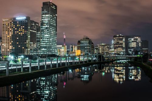 Free Illuminated cityscape of São Paulo reflecting in water at night. Modern architecture with a dramatic sky. Stock Photo