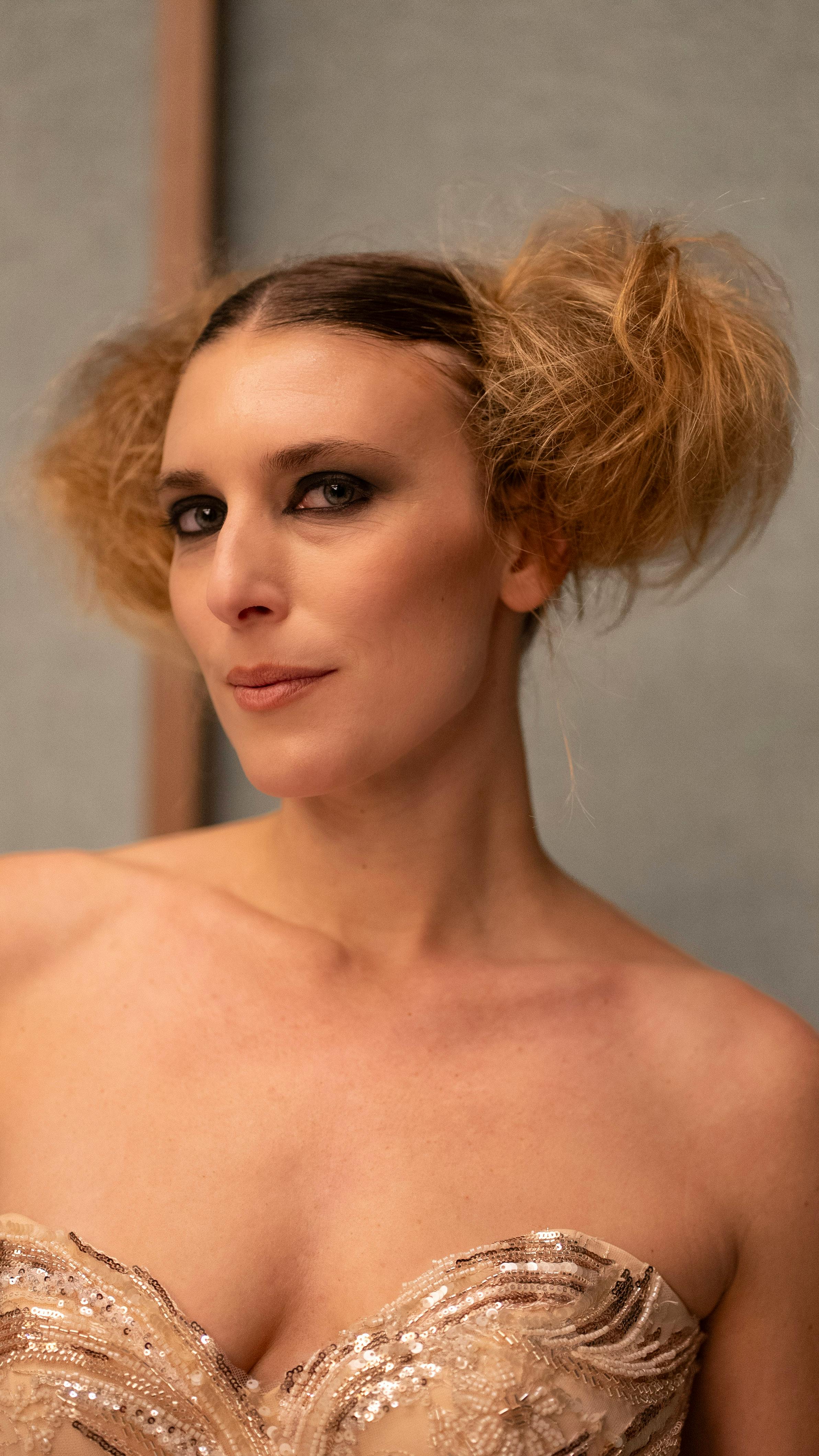 Chic fashion portrait of a woman with unique hairstyle in soft lighting.