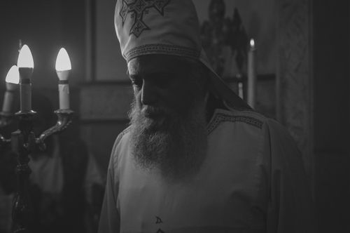 Free Black and white photo of an Orthodox priest during a candlelit religious ceremony in Cairo, Egypt. Stock Photo