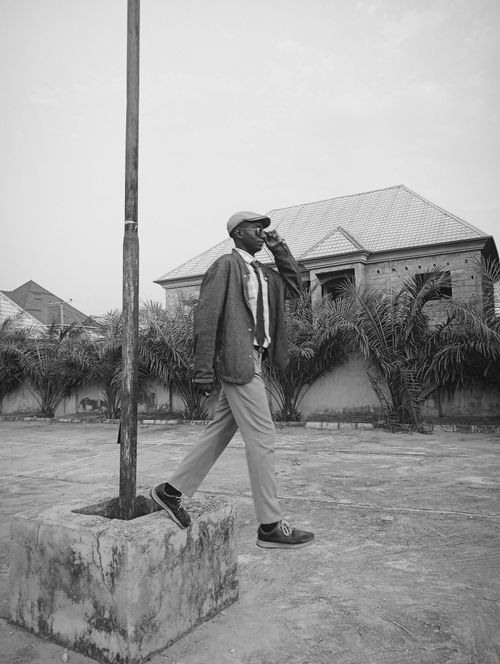 Free A stylishly dressed man walks past a lamppost in an outdoor setting, exuding sophistication. Stock Photo