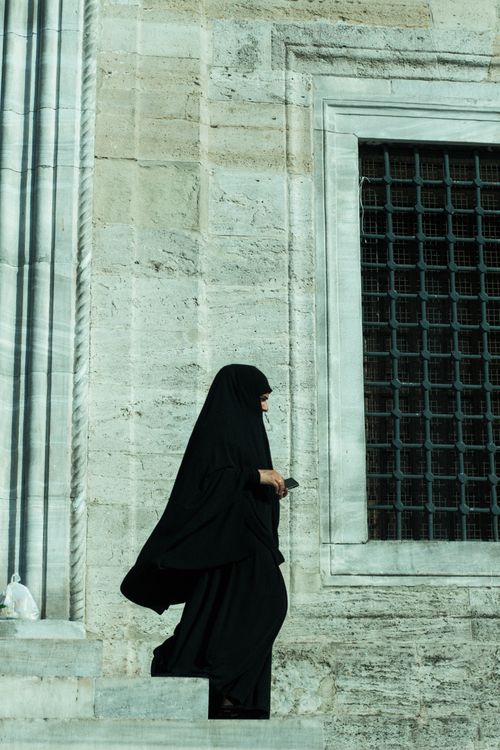 Free A woman in a black abaya walks by a historic building in Istanbul, Türkiye. Stock Photo