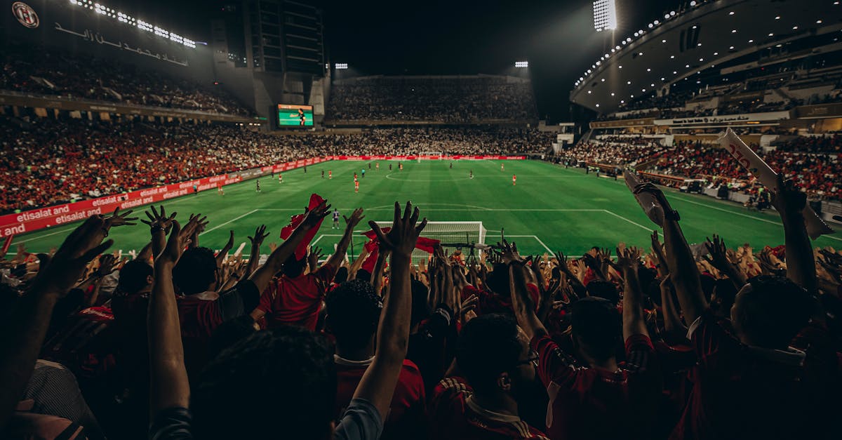 Lively football match with cheering fans in Abu Dhabi stadium at night.
