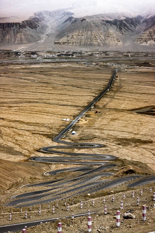 Free A long winding road stretches through a barren, mountainous landscape. Stock Photo