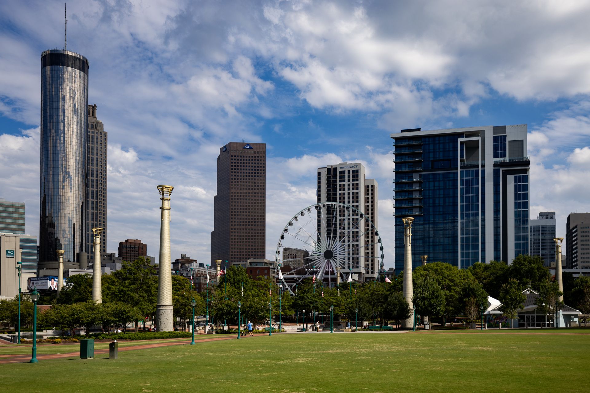 Downtown Atlanta skyline with Centennial Olympic Park, featuring modern skyscrapers, the Ferris wheel, and green space in daylight