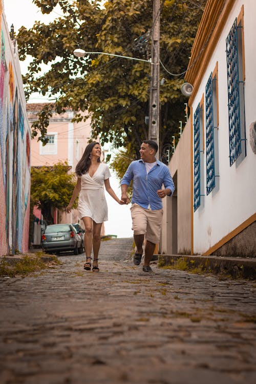 Woman Wearing White Dress Walking Beside of Man Wearing Blue Dress Shirt