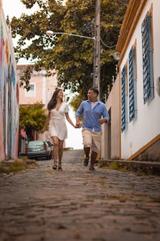 Couple happily running hand in hand down a charming cobblestone street in Olinda, Brazil.