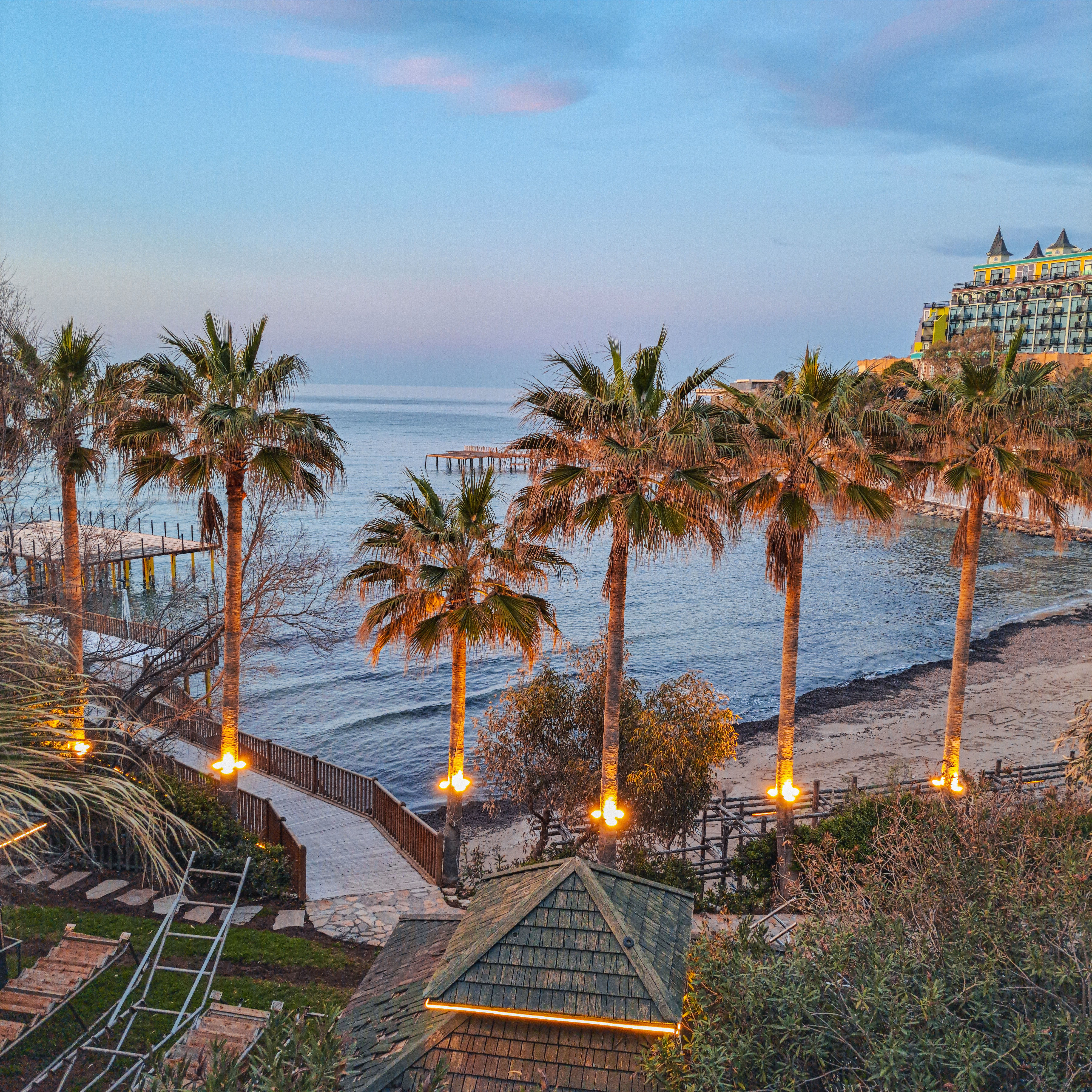 Stunning beachfront view with illuminated palm trees and a serene ocean at sunset.