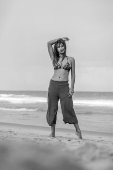Black and white photo of a woman posing on a sunny beach highlighting relaxation.