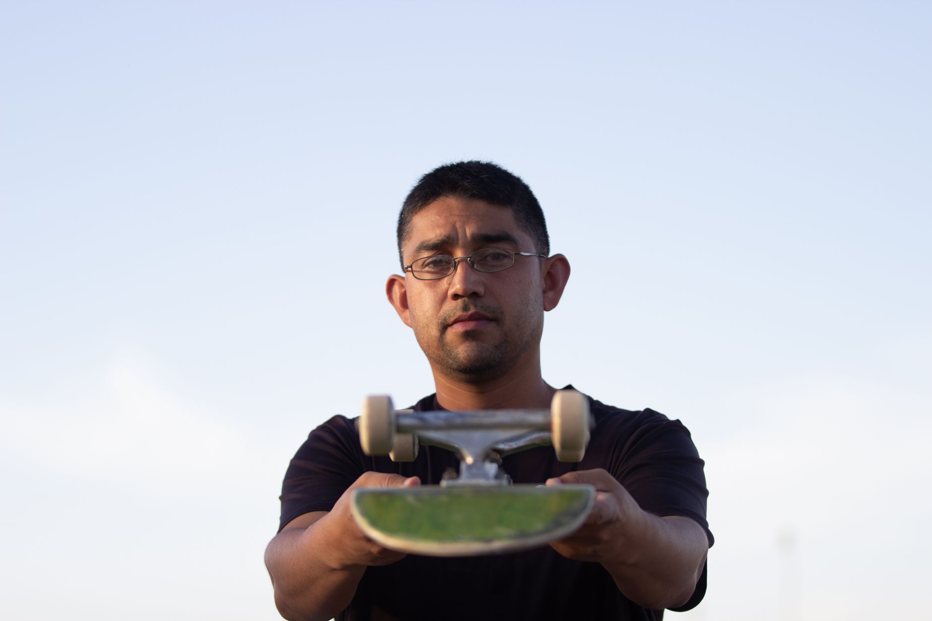 Skater inspecting deck dimensions and wheel hardware at a small independent shop in Houston