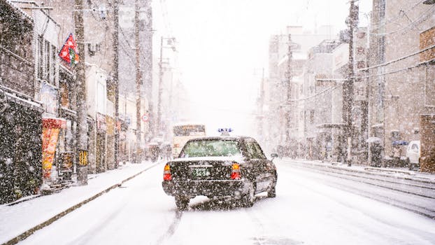 Taxi driving through a snowy street in a bustling urban winter scene.