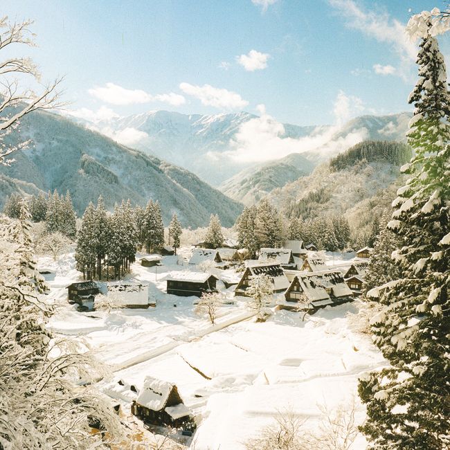 Scenic winter view of a snow-covered village nestled in majestic mountains.